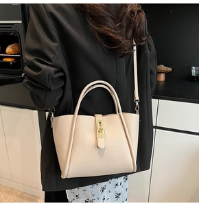 Dettaglio borsa a tracolla beige texture litchi con fibbia dorata e manici