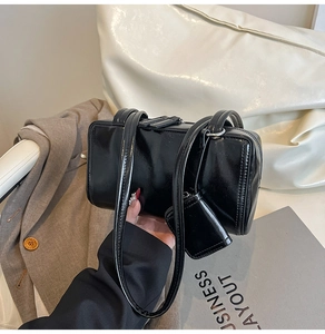 Detail of black glossy pillow bag with matching mini pouch and silver-tone hardware accents