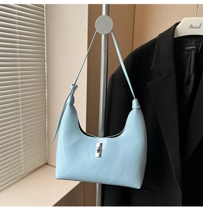Detail of light blue patent leather crescent bag with silver buckle and knotted strap