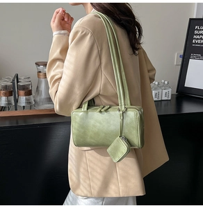 Detailed side view of a light green rectangular shoulder bag with a mini coin purse pendant