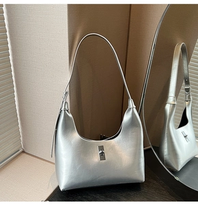 Detailed view of silver metallic crescent shoulder bag with elegant turn-lock closure