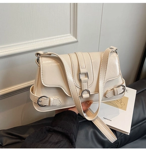 Détail d'un sac bandoulière en cuir verni crème avec boucles métalliques argentées