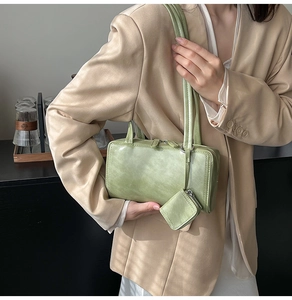 Detail of light green rectangular shoulder bag with matching coin purse on a blazer model