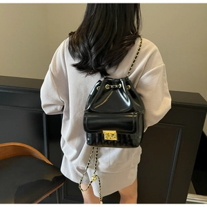 Détail du sac à dos seau en cuir verni noir avec bretelles en chaîne dorée sur modèle