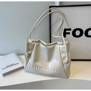Close-up of cream leather tote bag featuring embossed logo detail and drawstring accents