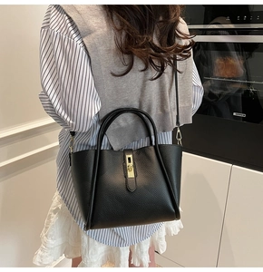 Dettaglio borsa tote in pelle nera con chiusura dorata e tracolla sottile in pelle