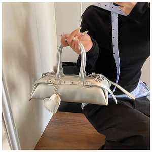 Detalle de bolso plateado con colgante de corazón y correas con hebillas de moda