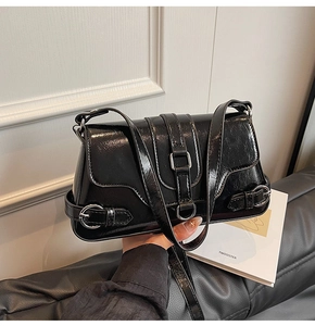 Détail du sac sous le bras en cuir verni plissé noir avec boucles métalliques