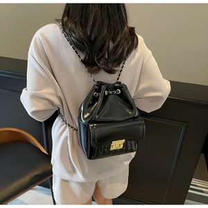 Détail d'un sac à dos seau noir brillant avec chaînes métalliques et poche avant à verrou