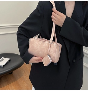 Detail of light pink shoulder bag with vintage texture and matching small pendant charm