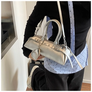 Bolso almohada plateado metalizado con ojales punk y colgante de corazón en una modelo