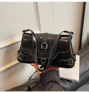 Détail du sac bandoulière en cuir verni noir avec boucles et sangles en métal argenté