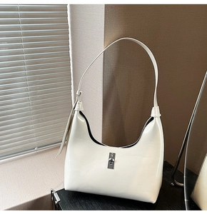 Detail view of white glossy patent leather crescent shoulder bag with silver metal lock
