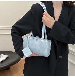 Detail of light blue shoulder bag with leather texture and matching mini charm pouch