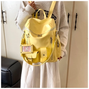 Close-up of bright yellow multi-pocket backpack showing functional zippers and cute cat card