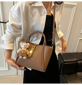 Dettaglio borsa in pelle marrone martellata con chiusura dorata e ciondolo