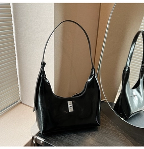 Detail of black glossy leather hobo bag featuring a silver rotating metal clasp closure