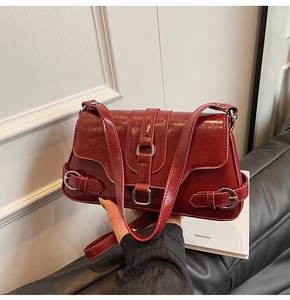 Détail du sac à bandoulière en cuir ciré rouge foncé avec boucles métalliques argentées