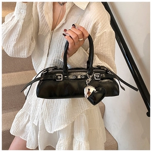 Detalle de bolso punk negro con hebillas plateadas y un colgante en forma de corazón
