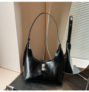 Detail of glossy black patent leather crescent bag with silver metallic turn-lock closure