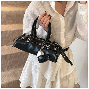 Detalle del bolso cilíndrico negro con textura cuero, colgante corazón y cremallera borla