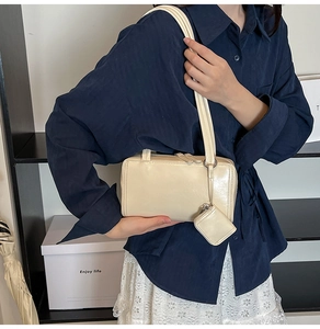 Detail of beige shoulder bag with glossy finish and matching mini coin purse attachment