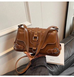 Détail d'un sac porté épaule vintage marron en cuir huilé brillant avec boucle décorative