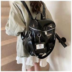 Detail of black glossy faux leather backpack with silver zippers and side pockets