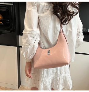 Detail of light pink patent leather hobo bag showing metallic clasp and glossy finish