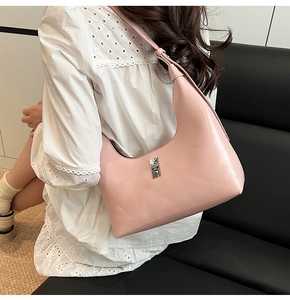Close-up of pink hobo crescent bag with silver metallic twist lock on a white lace dress