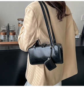 Detail of a black glossy leather shoulder bag with a matching mini square coin purse