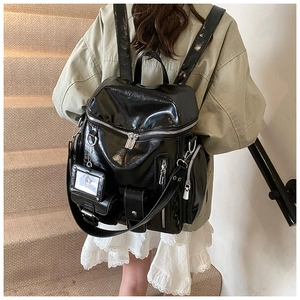 Detail of black glossy backpack featuring functional zipper pockets and shiny PU texture