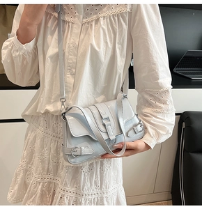 Détail d'un sac bandoulière en cuir verni bleu clair avec boucles porté par un mannequin