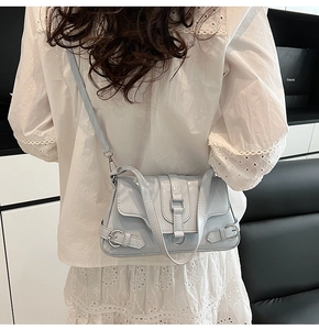 Vue arrière d'un modèle portant un sac à épaule en cuir verni bleu clair à boucles