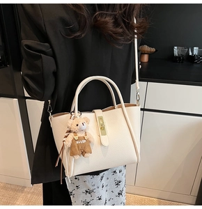 Dettaglio borsa in pelle bianco crema con ciondolo a forma di orso e chiusura dorata