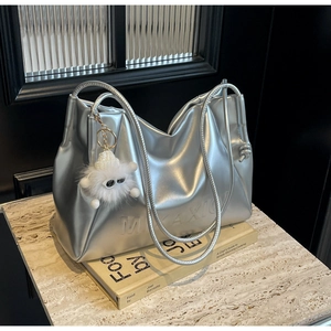 Detail of silver metallic tote bag with drawstring texture and fluffy plush charm