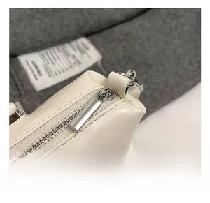 Detailed macro view of high-quality silver metal zipper on cream white leather handbag