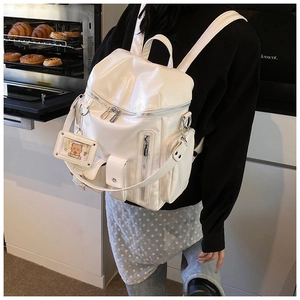 Detail of white glossy PU leather backpack with silver zippers and a cute bear card holder