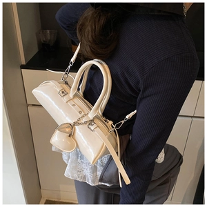 Bolso tipo almohada de charol blanco usado por modelo destaca su acabado de espejo