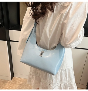 Detail of light blue glossy leather hobo bag with elegant silver rotating metal lock