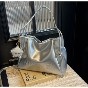 Detail of silver metallic tote bag with embossed logo and fuzzy white monster charm
