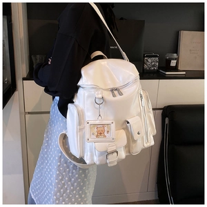 Detail of white PU leather backpack with multiple pockets and a cute bear charm