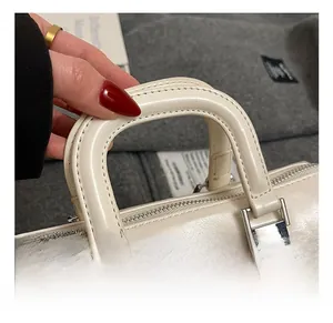Close-up of cream leather handbag handle with fine stitching and silver hardware