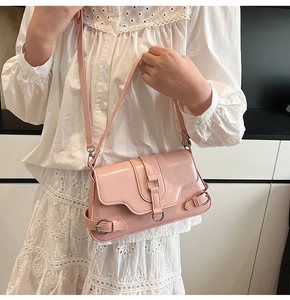 Détail du sac à bandoulière rose clair avec boucle sur robe en dentelle blanche