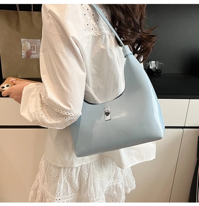 Detail of light blue patent leather hobo bag with shiny silver rectangular twist lock