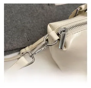 Close-up of premium silver metal hardware and neat stitching on a beige leather handbag