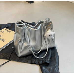 Silver metallic pleated tote bag with plush charm and embossed logo on leather jacket