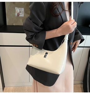 Detail of a minimalist off-white crescent bag with silver metallic buckle on a model