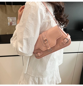 Gros plan d'un sac sous le bras en cuir rose avec trois anneaux et bandoulière réglable