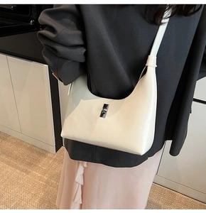 Close-up of cream-white leather Hobo bag with silver twist lock on a fashion model